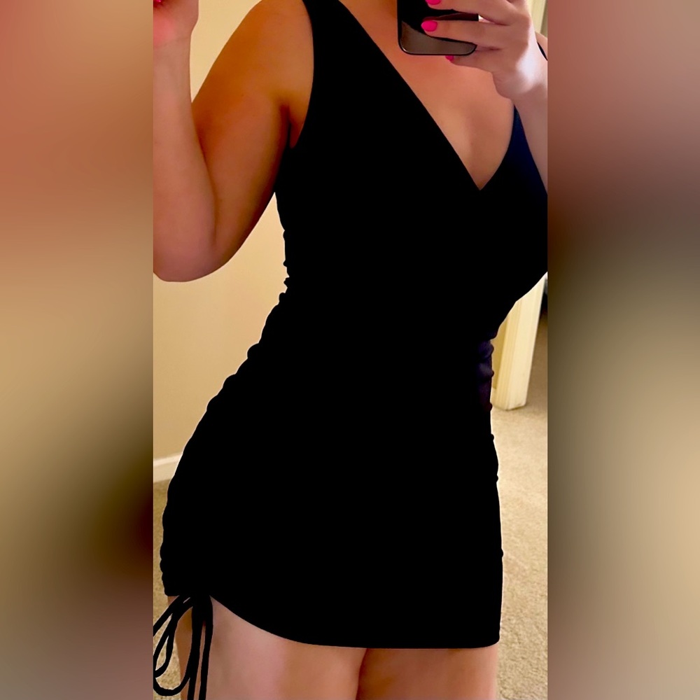 Brand new short black dress with side rouching and string.